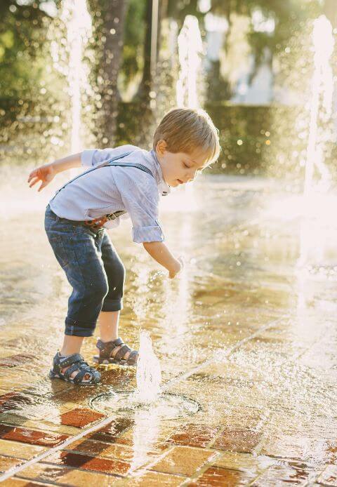 Image of a child playing in a water fountain